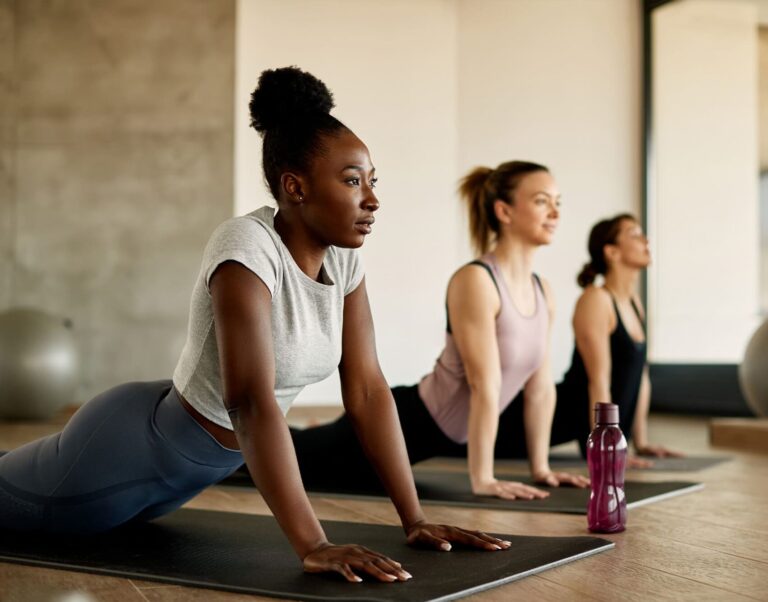 Drei Menschen machen auf Yoga-Matten gemeinsam eine Übung
