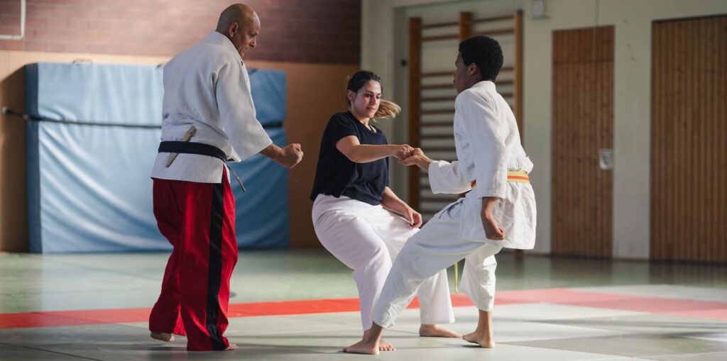 Übungsleiter leitet einen Judo-Kampf zwischen einer Frau und einem Mann