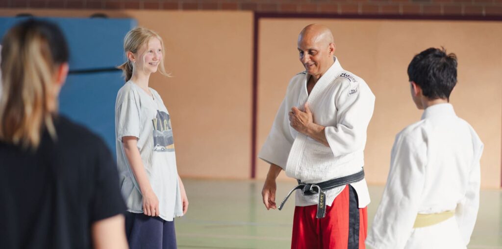 Judo-Übungsleiter erklärt 3 Kindern eine Übung